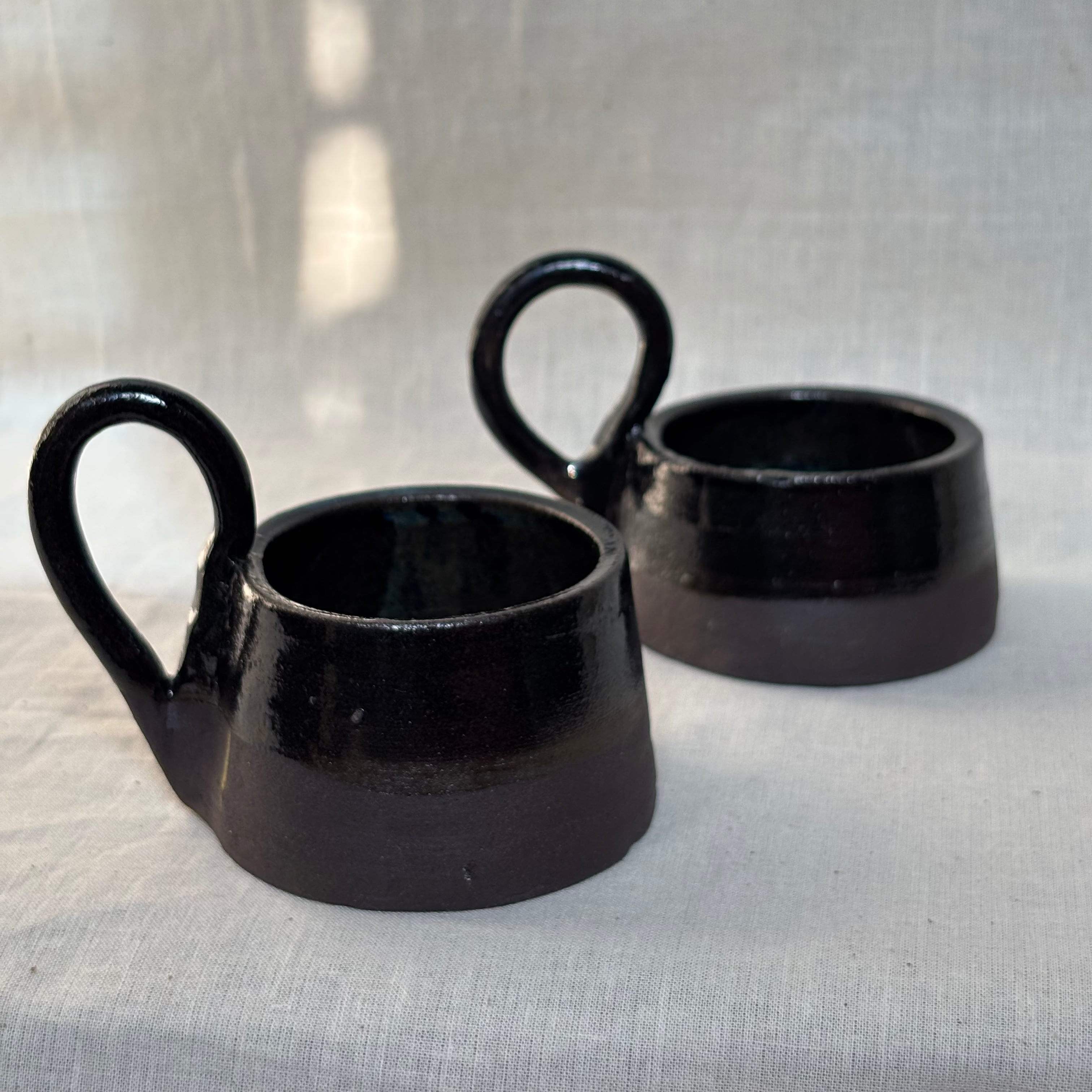 Ceramic candle holders made from black clay with transparent glaze on the inside and half outside