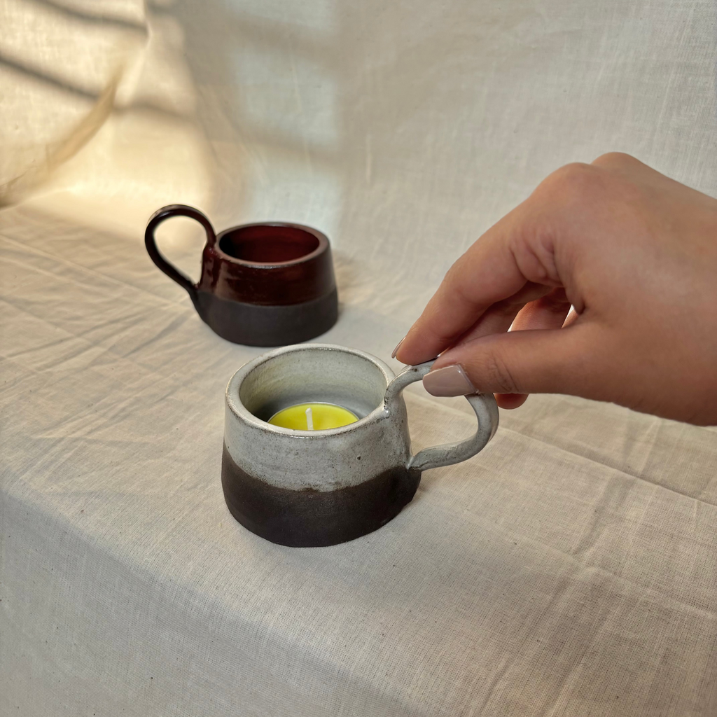 two ceramic candle holders, each half glazed on black clay, one red and one white