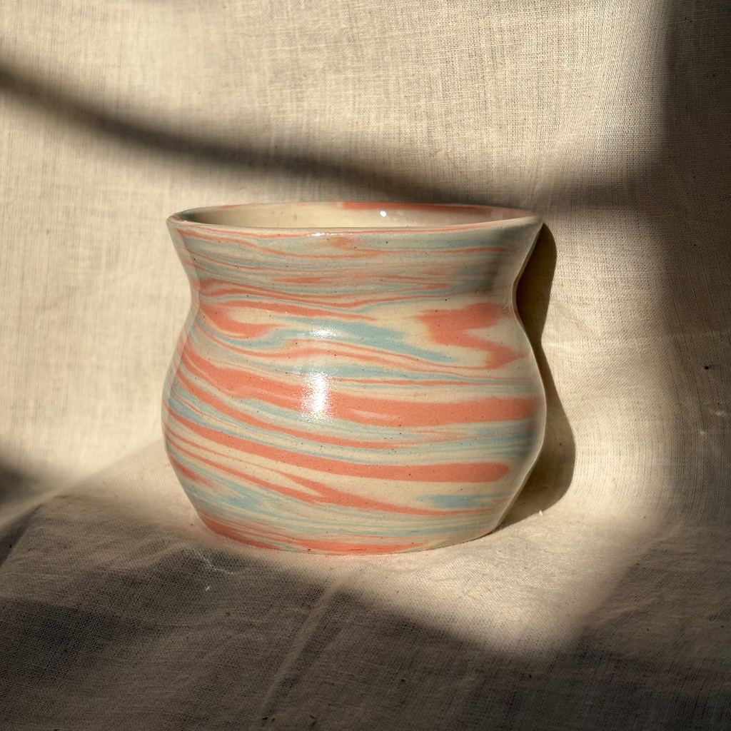 Ceramic cup with marbled design on a textured fabric background