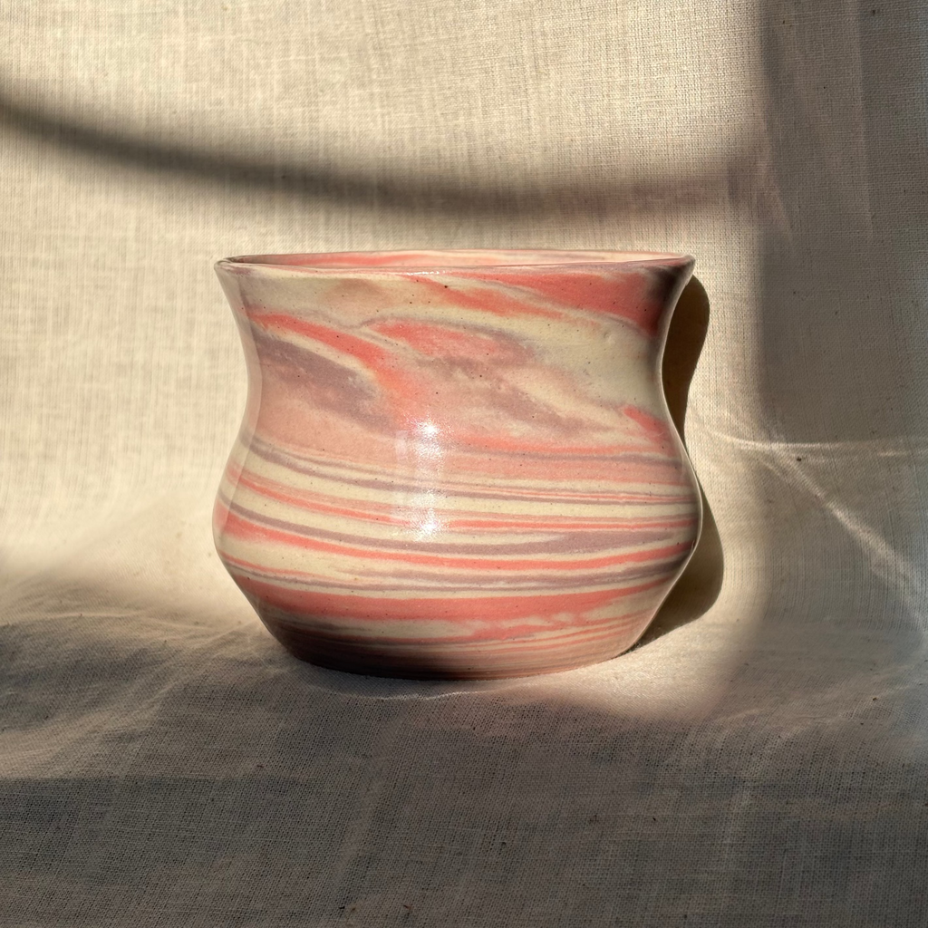 Ceramic cup with marbled design on a textured fabric background