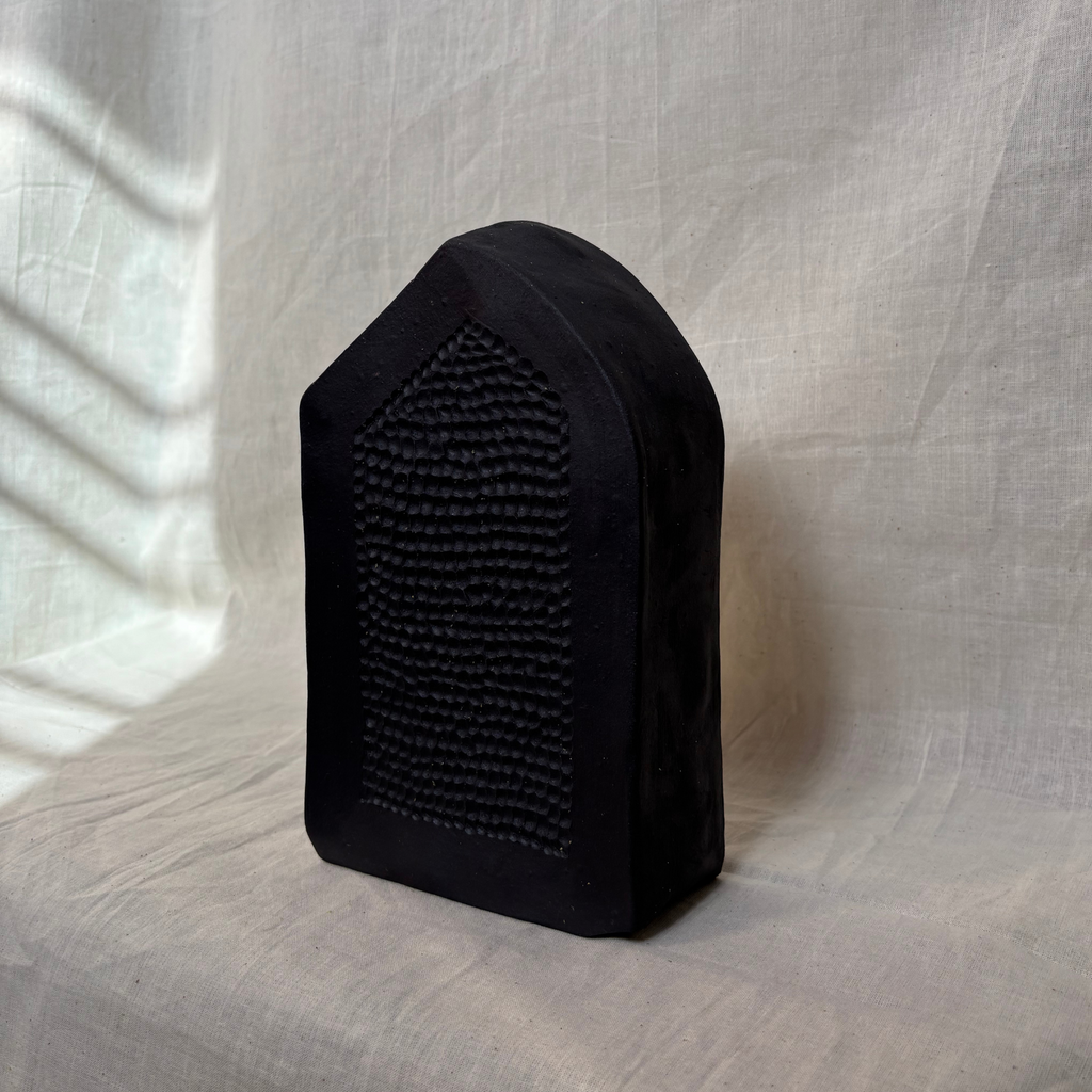 Black vase with carved surface on the front